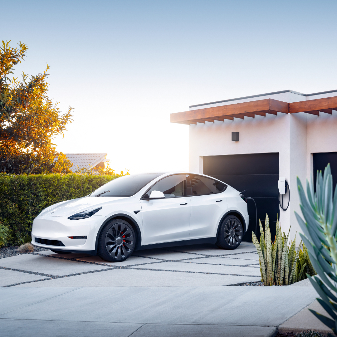 Model Y an einem Wall Connector angeschlossen, von weiter weg fotografiert