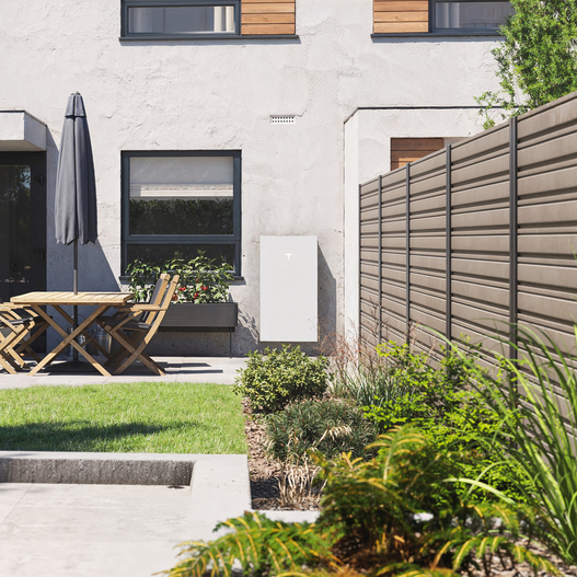 Powerwall 3 draußen in einem Garten bei strahlender Sonne